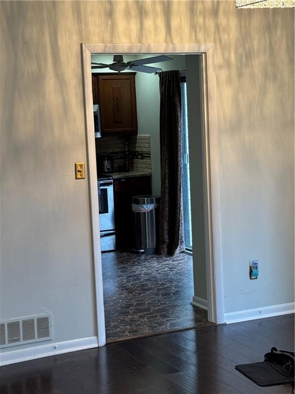 interior space featuring visible vents, electric stove, stainless steel microwave, ceiling fan, and dark wood-style flooring