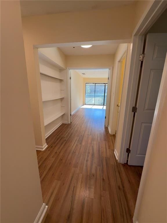 corridor featuring dark wood-type flooring and built in features