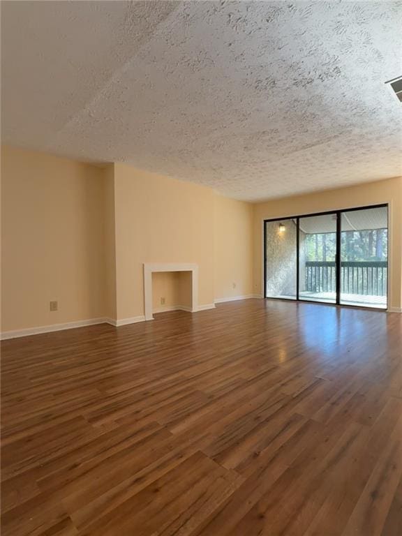 empty room featuring a textured ceiling, baseboards, and wood finished floors