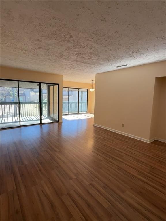 unfurnished room with a textured ceiling and dark wood-type flooring