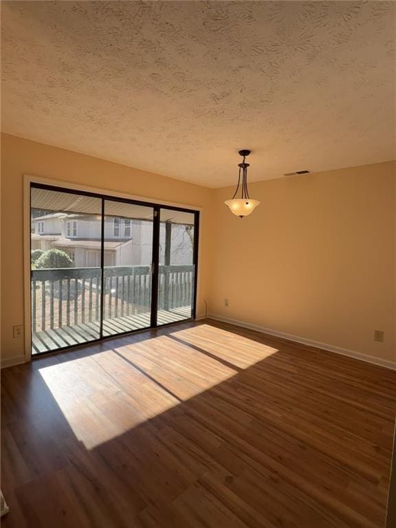 empty room featuring dark wood-type flooring and a textured ceiling