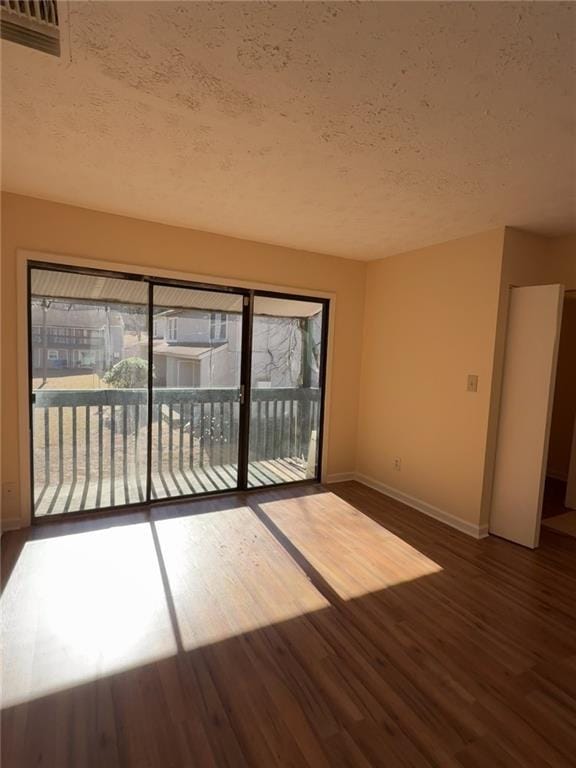 empty room featuring a textured ceiling, a wealth of natural light, and dark hardwood / wood-style floors