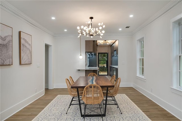 dining area with baseboards, visible vents, wood finished floors, and ornamental molding