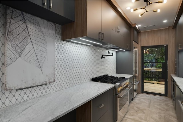 kitchen featuring modern cabinets, stainless steel range, light stone counters, and backsplash