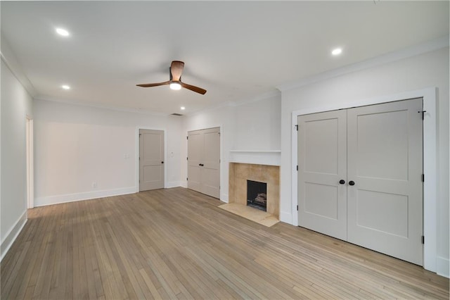 unfurnished living room featuring ornamental molding, a fireplace, light wood-style flooring, and baseboards