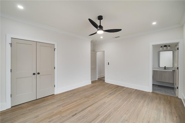 unfurnished bedroom featuring ensuite bathroom, visible vents, baseboards, light wood-style floors, and crown molding