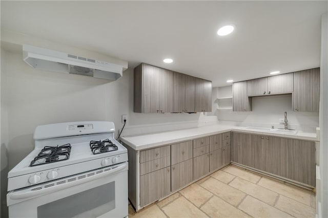 kitchen with white gas range, recessed lighting, stone tile flooring, a sink, and under cabinet range hood