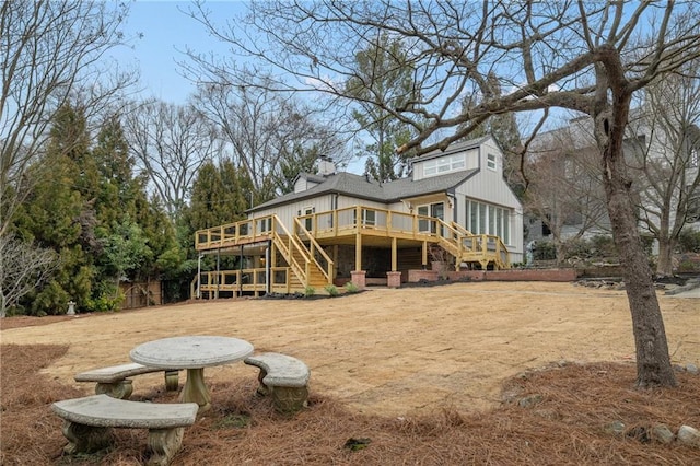 rear view of house with a chimney, stairway, and a wooden deck