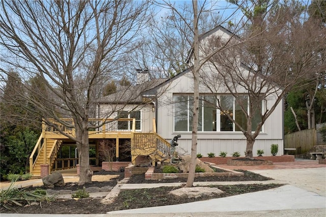 view of front facade featuring a chimney, stairway, and a wooden deck