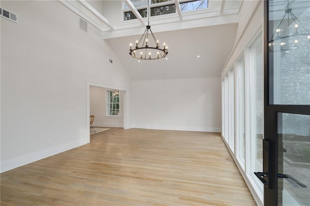 unfurnished room with visible vents, a notable chandelier, and a towering ceiling