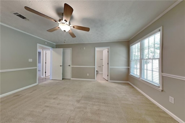 empty room featuring ceiling fan, light colored carpet, a textured ceiling, and ornamental molding