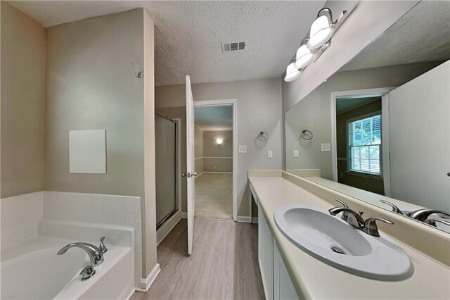 bathroom with separate shower and tub, vanity, wood-type flooring, and a textured ceiling