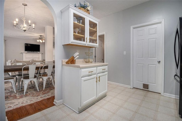 kitchen featuring white cabinetry, pendant lighting, ceiling fan with notable chandelier, and a textured ceiling