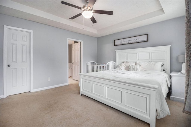 carpeted bedroom with ceiling fan and a raised ceiling