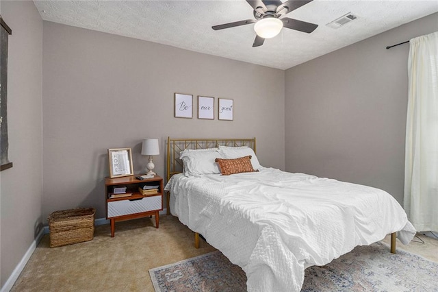 bedroom featuring light colored carpet, a textured ceiling, and ceiling fan