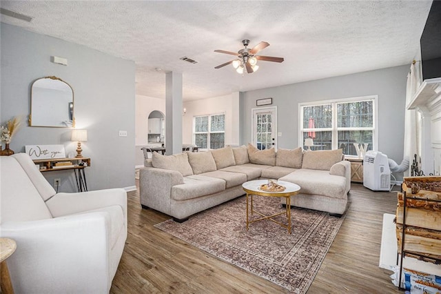 living room with hardwood / wood-style flooring, ceiling fan, and a textured ceiling