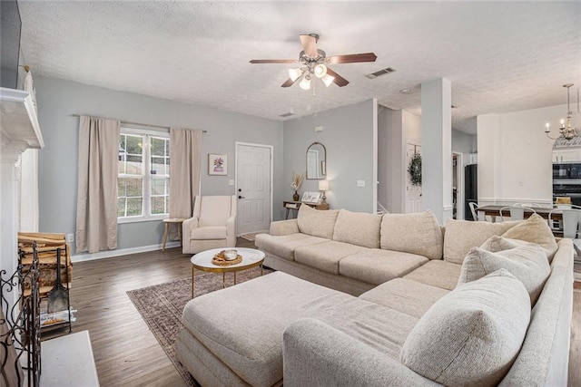 living room featuring ceiling fan with notable chandelier, a textured ceiling, and dark hardwood / wood-style flooring