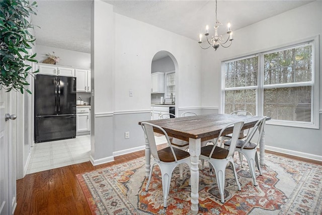 dining room with an inviting chandelier, sink, and light wood-type flooring