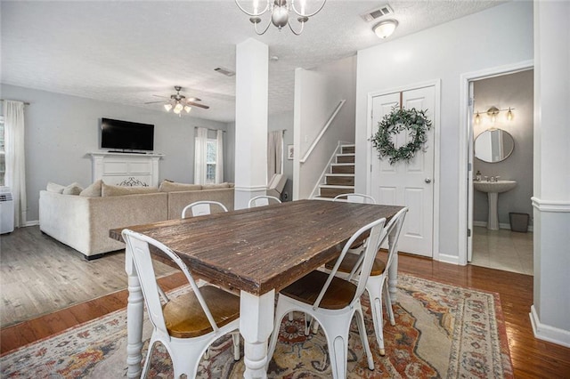 dining area with sink, ceiling fan with notable chandelier, a textured ceiling, and hardwood / wood-style flooring