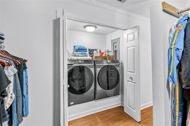 laundry area with washing machine and clothes dryer, hardwood / wood-style flooring, and crown molding