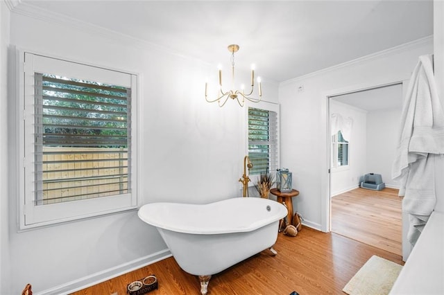 bathroom with a bathtub, a chandelier, wood-type flooring, and ornamental molding