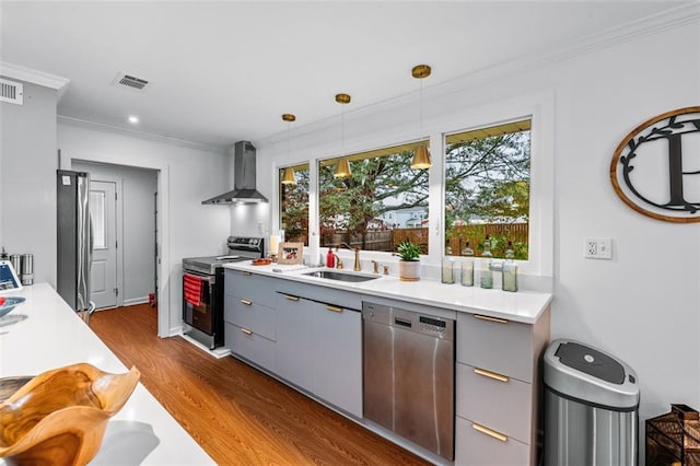 kitchen featuring stainless steel appliances, dark hardwood / wood-style flooring, hanging light fixtures, sink, and wall chimney range hood