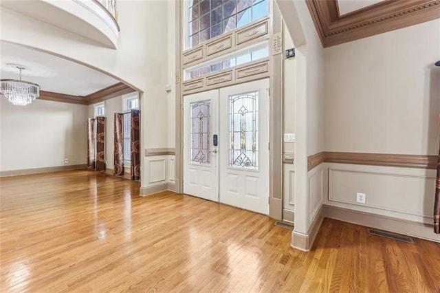 entrance foyer featuring an inviting chandelier, crown molding, and light hardwood / wood-style flooring