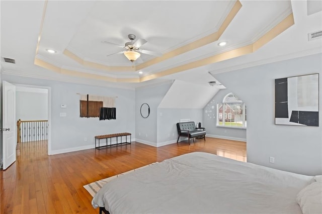 bedroom featuring a tray ceiling, crown molding, hardwood / wood-style floors, baseboards, and recessed lighting