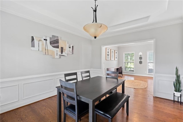dining space featuring ornamental molding, wainscoting, dark wood finished floors, and a decorative wall