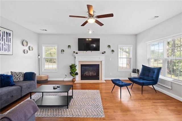 living room with ceiling fan, a fireplace with flush hearth, wood finished floors, and baseboards