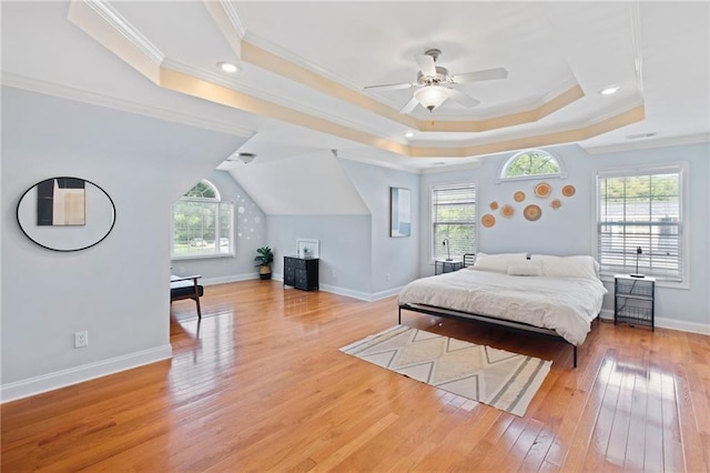bedroom featuring light wood-style flooring, a raised ceiling, ornamental molding, and baseboards