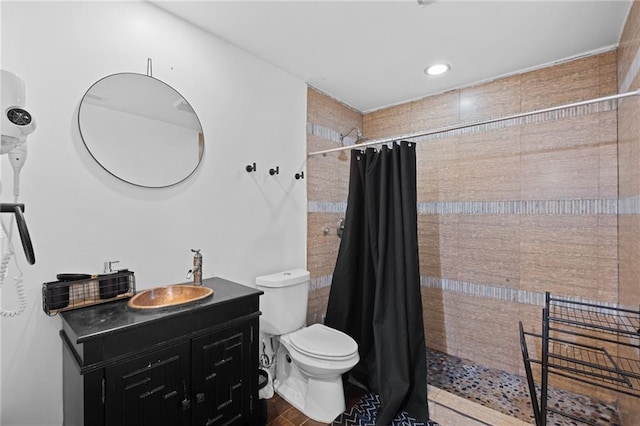 full bathroom featuring tiled shower, toilet, and vanity