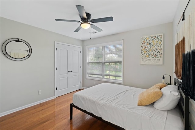bedroom with baseboards, light wood-style flooring, ceiling fan, and a closet