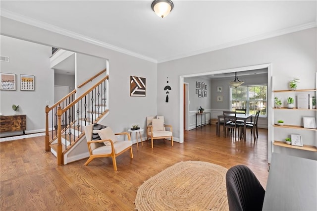 living room featuring stairs, ornamental molding, light wood-style flooring, and baseboards