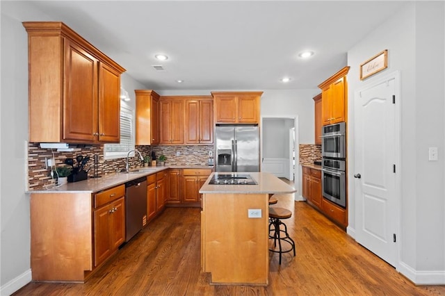 kitchen featuring stainless steel appliances, a sink, a breakfast bar area, dark wood-style flooring, and a kitchen island