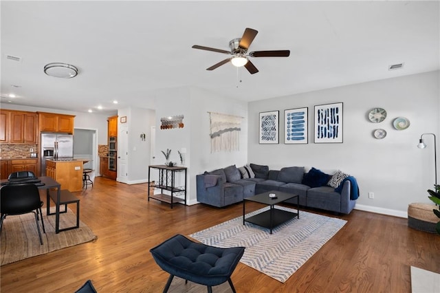 living area featuring a ceiling fan, baseboards, dark wood finished floors, and recessed lighting