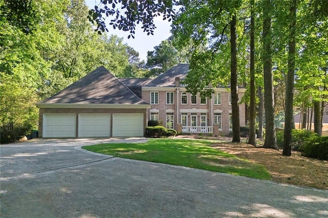 colonial inspired home featuring driveway, a garage, and brick siding