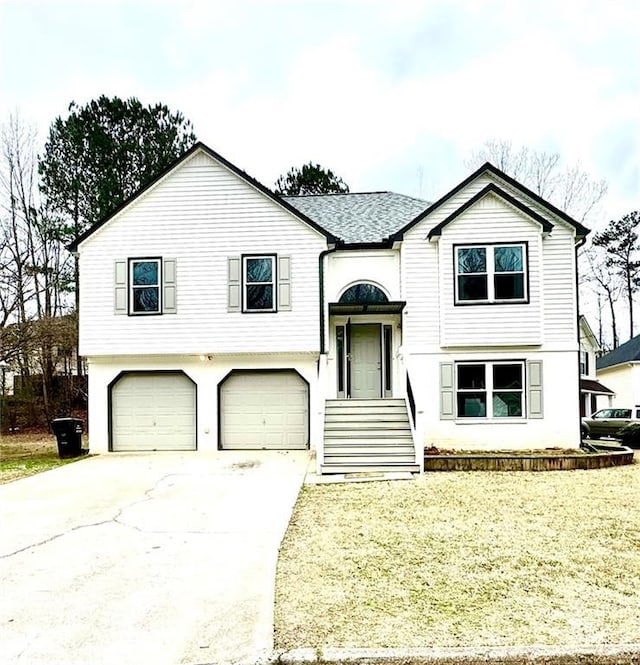 raised ranch featuring a front yard, driveway, and an attached garage