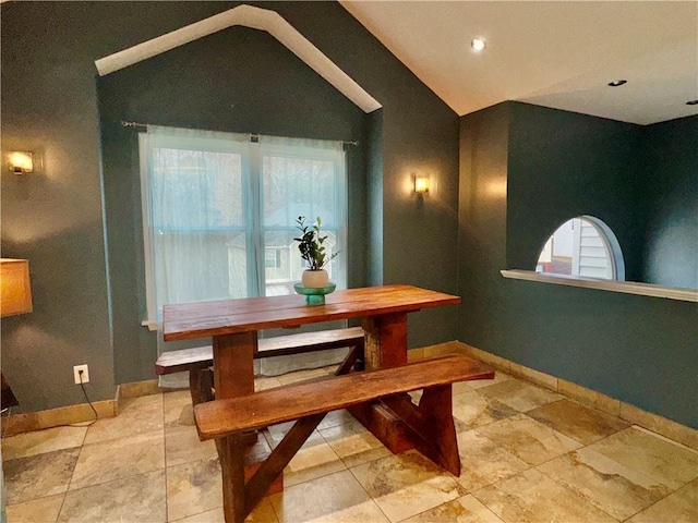 dining space with baseboards and vaulted ceiling