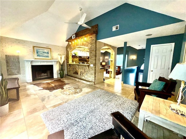 living room featuring ceiling fan, light tile patterned floors, a fireplace, visible vents, and vaulted ceiling