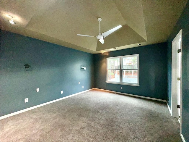 empty room with lofted ceiling, carpet, baseboards, and a raised ceiling