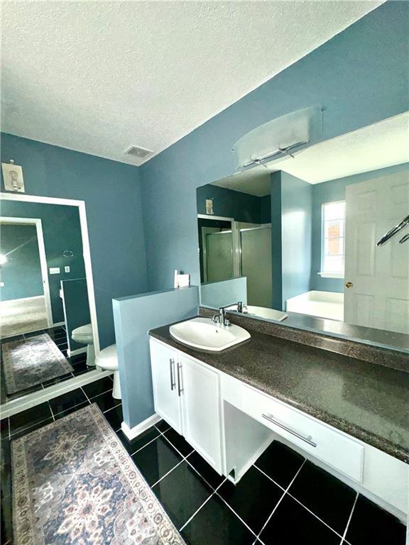 bathroom with a textured ceiling, tile patterned flooring, toilet, visible vents, and vanity