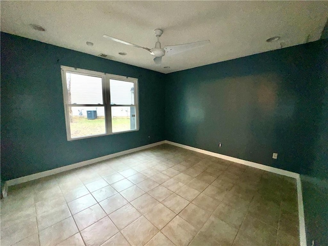 spare room featuring light tile patterned flooring, a ceiling fan, and baseboards