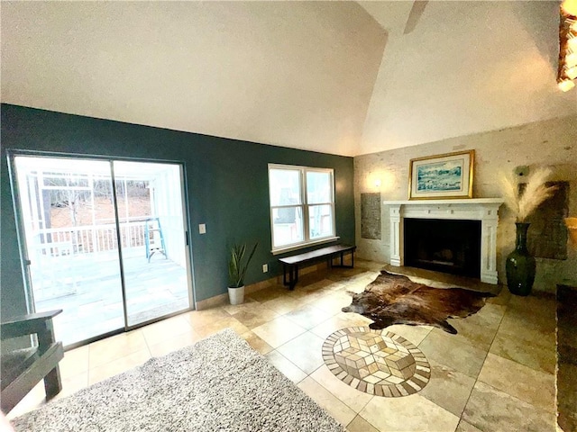 living area with high vaulted ceiling, a fireplace, baseboards, and light tile patterned floors