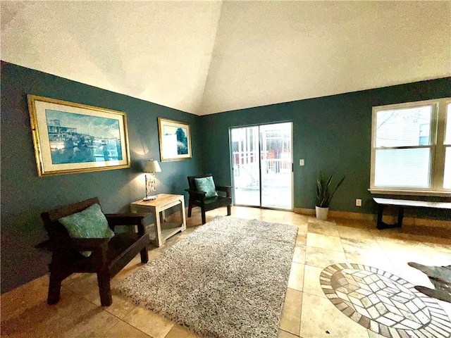 living area featuring vaulted ceiling, a textured ceiling, and baseboards