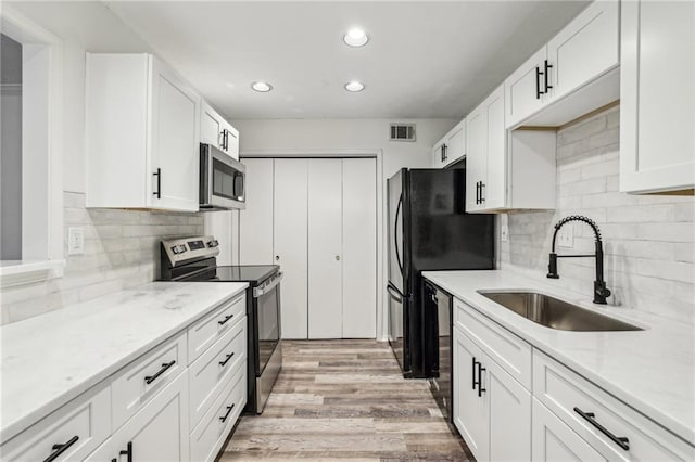 kitchen with stainless steel appliances, light hardwood / wood-style floors, sink, and white cabinets