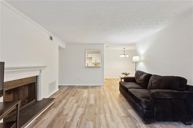 living room featuring light wood-type flooring, visible vents, ornamental molding, and a fireplace with raised hearth