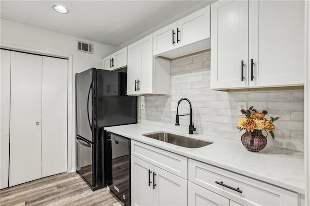 kitchen with visible vents, dishwasher, light countertops, white cabinetry, and a sink