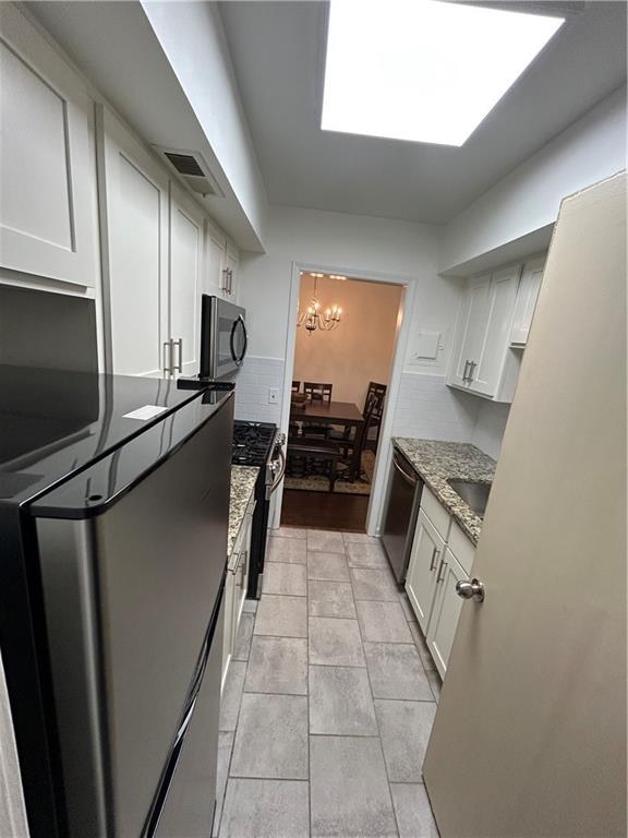 6851 Roswell Rd Unit O10, Atlanta, GA 30328 - kitchen featuring stainless steel appliances, tasteful backsplash, a chandelier, light stone counters, and white cabinets
