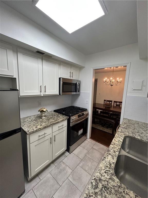 6851 Roswell Rd Unit O10, Atlanta, GA 30328 - kitchen with appliances with stainless steel finishes, a chandelier, white cabinets, and light stone countertops